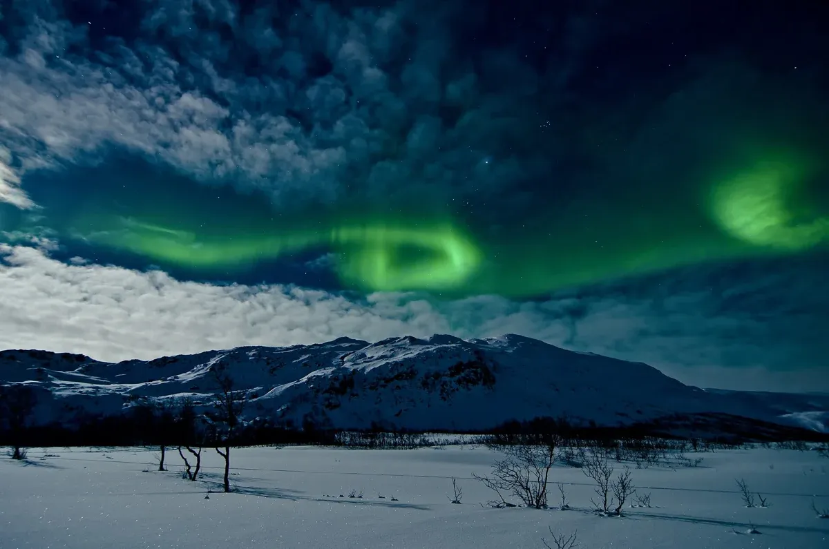 Northern lights over a snowy valley near Tromsø, hoped for on an evening Tromso reindeer sledding tour