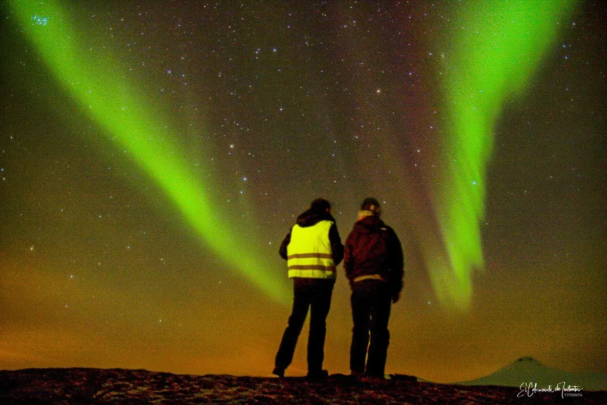 Two people watching green northern lights north of Tromsø, as on a reindeer and northern lights tour